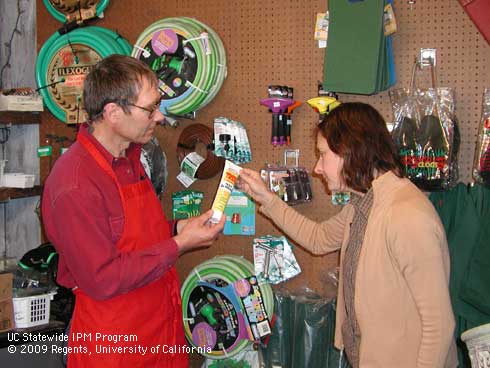 Retail nursery employee and customer look at a tube of tanglefoot.