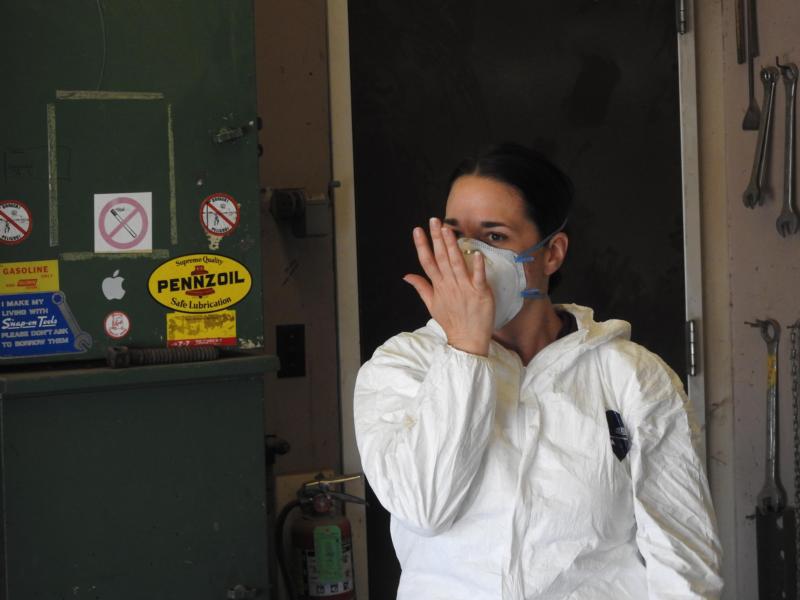 A person with their hand up against the front of a filtering facepiece.